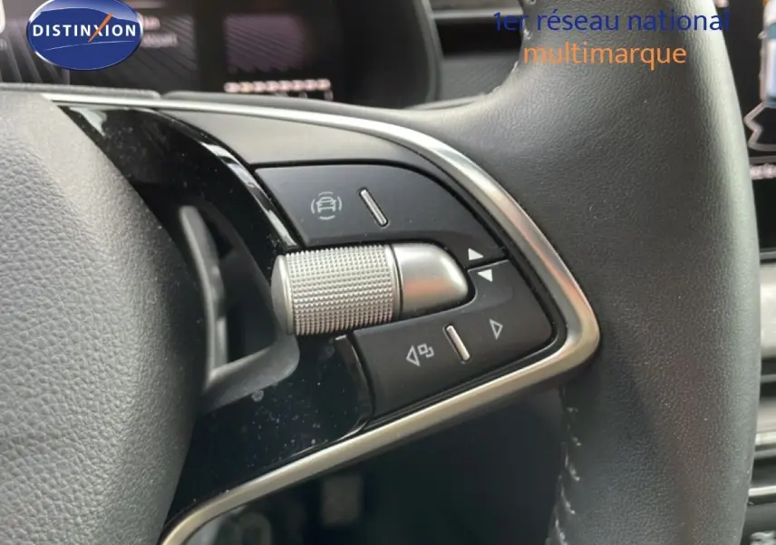 Gros plan sur les commandes du volant en cuir noir de la Skoda Scala 2025, avec molette et boutons multifonctions.