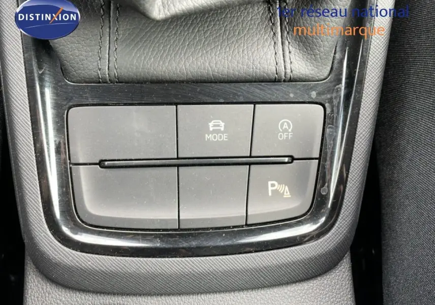 Gros plan sur les boutons de commande du mode de conduite et assistance au stationnement d’un Skoda Scala blanc glacier.
