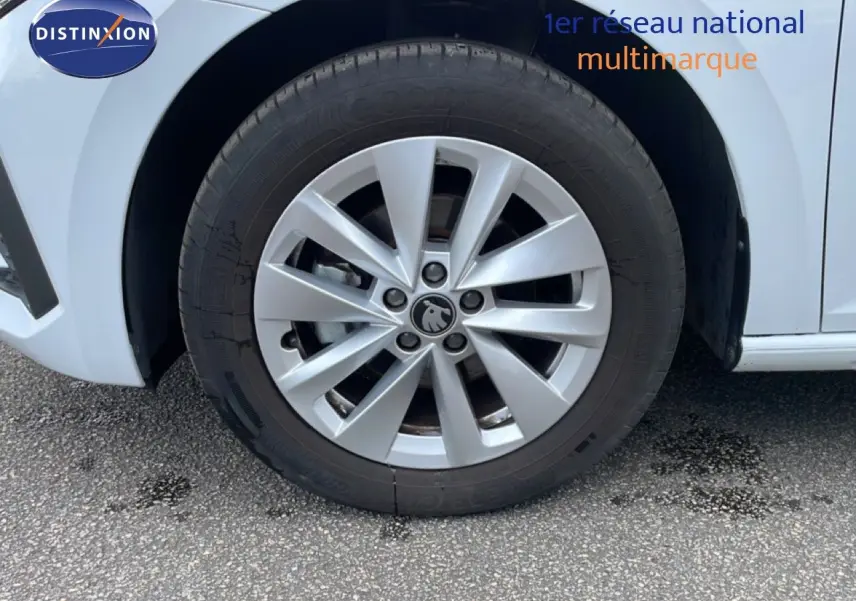 Gros plan sur la roue avant gauche d'une Skoda Scala blanc glacier avec jante alliage à dix branches.