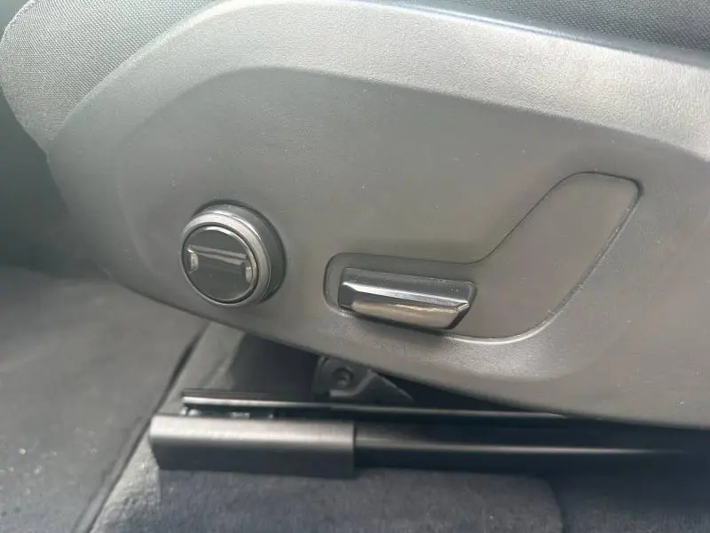 Gros plan sur les commandes de réglage électrique du siège avant côté gauche dans un Volvo XC60 gris 2024.