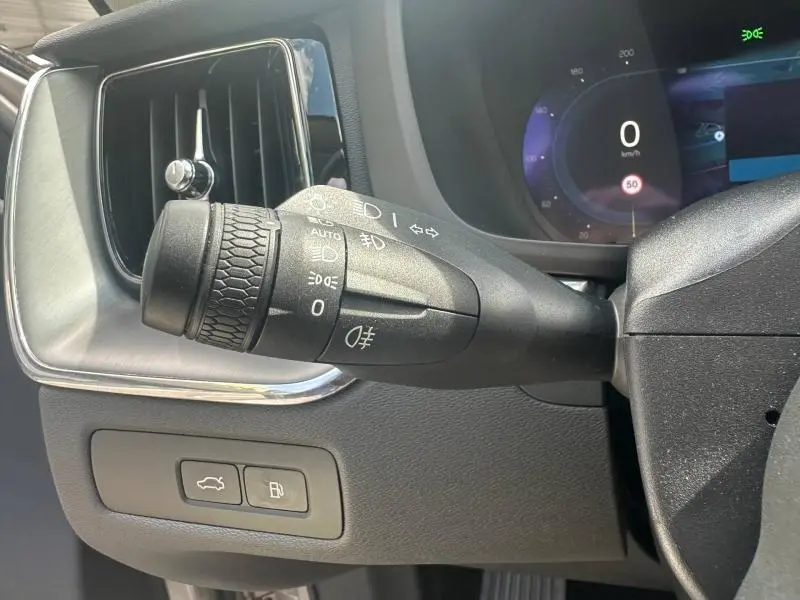 Gros plan sur la commande des feux et clignotants à gauche du volant dans l’habitacle gris du Volvo XC60 2024.