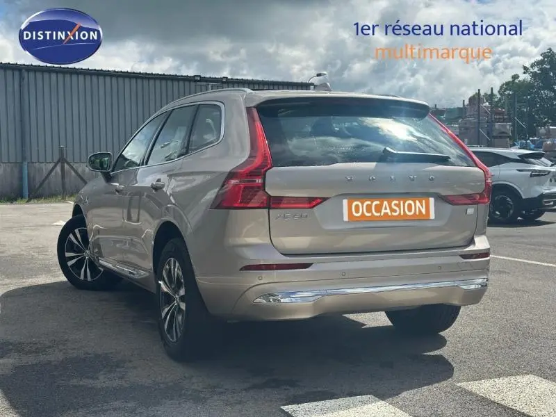 Vue 3/4 arrière droite d'un Volvo XC60 gris avec feux arrière LED en forme de L et logo "OCCASION" sur le coffre.