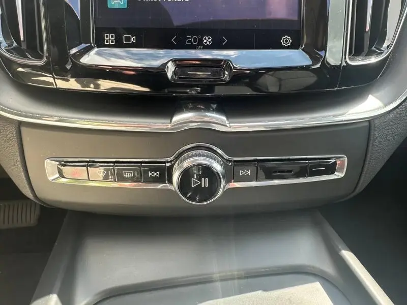 Gros plan sur la console centrale du Volvo XC60 gris 2024, avec commandes audio et finition chrome élégante.