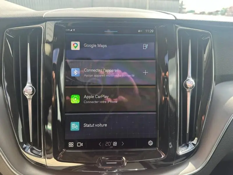 Vue rapprochée de l'écran tactile central noir du tableau de bord du Volvo XC60 gris 2024 avec interface Google Maps et Apple CarPlay.