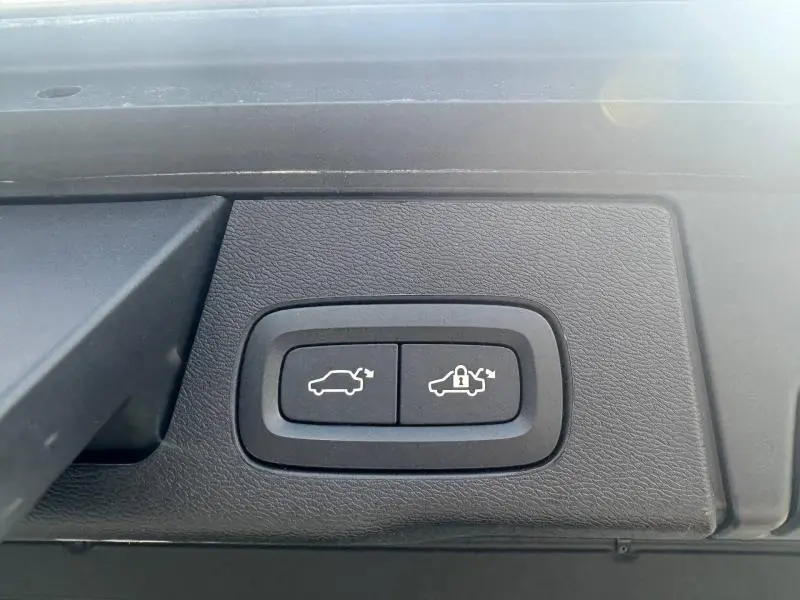 Gros plan sur les boutons d'ouverture et de verrouillage électrique du coffre d'un Volvo XC60 gris 2024.