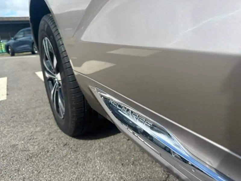 Gros plan sur le côté gauche arrière gris du Volvo XC60 2024 avec logo "Recharge" chromé près de la roue.