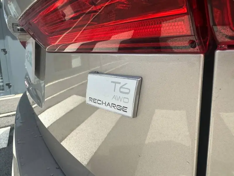 Gros plan sur l'arrière droit gris du Volvo XC60 2024 avec le badge T6 AWD Recharge sous le feu arrière.