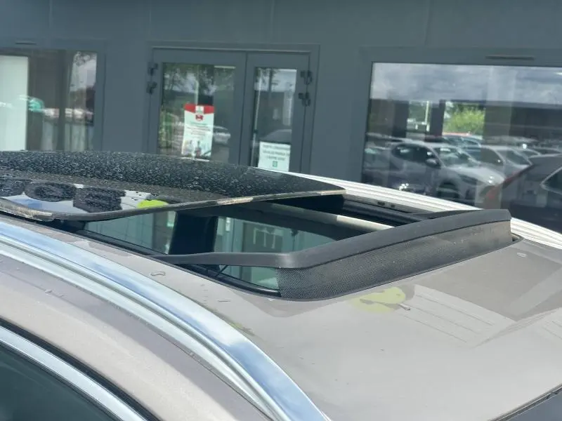 Toit ouvrant panoramique ouvert sur un Volvo XC60 gris, vue rapprochée du toit avec rails chromés visibles.
