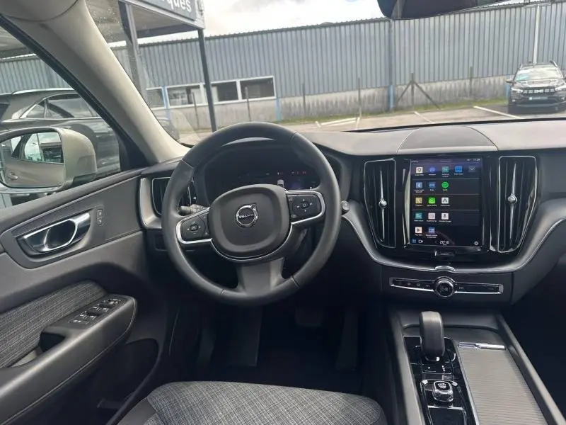 Vue intérieure avant du Volvo XC60 2024 hybride rechargeable, avec tableau de bord moderne et écran tactile central.