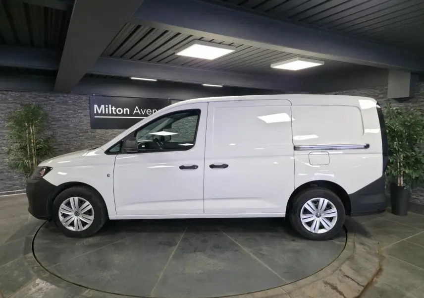 Vue de profil côté gauche d’un utilitaire Volkswagen Caddy Cargo blanc avec portes coulissantes et jantes acier.