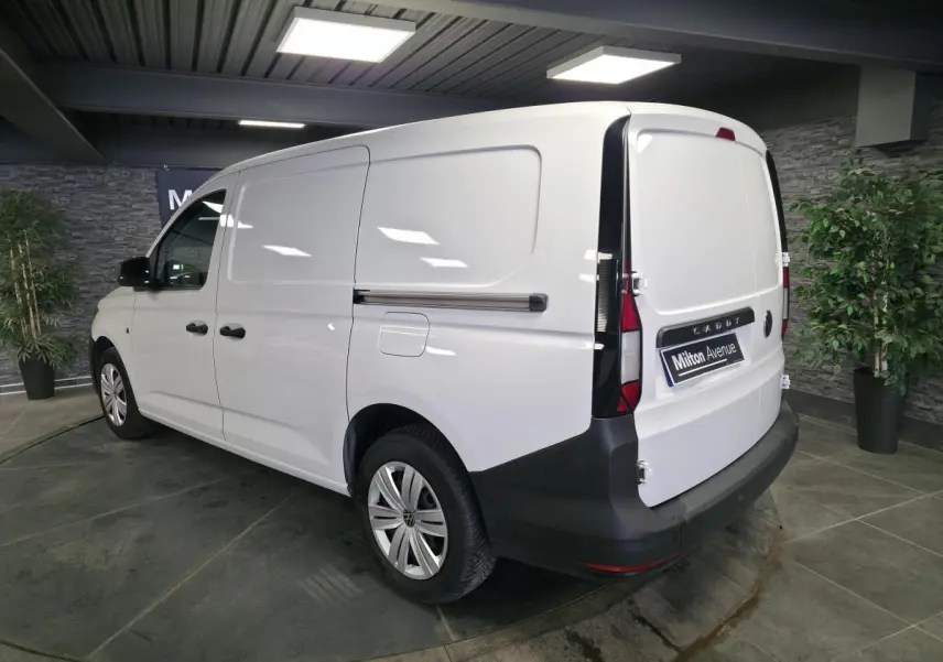 Vue 3/4 arrière droite du Volkswagen Caddy Cargo blanc, fourgon avec portes arrière battantes et pare-chocs noir.