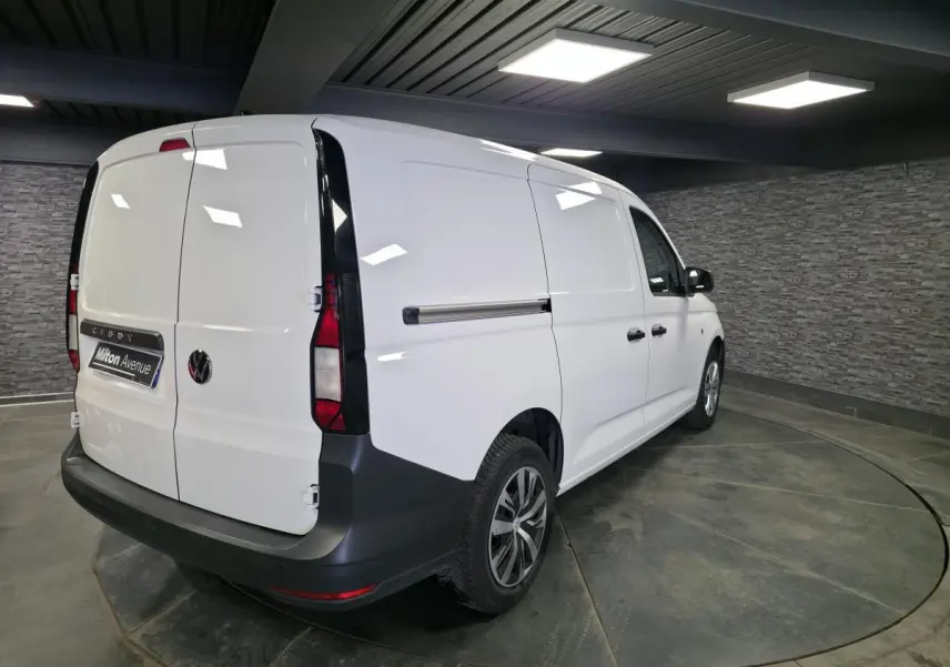 Vue 3/4 arrière droite d'un Volkswagen Caddy Cargo blanc avec portes battantes arrière et jantes en acier noires.