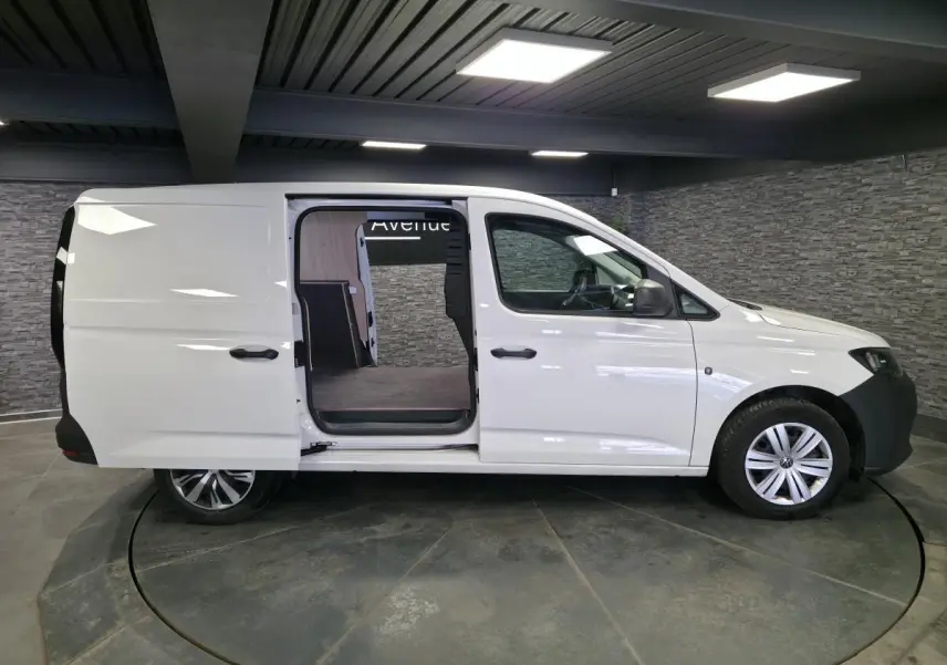 Vue latérale droite d’un Volkswagen Caddy Cargo blanc 2023 avec porte coulissante ouverte et jantes alliage.