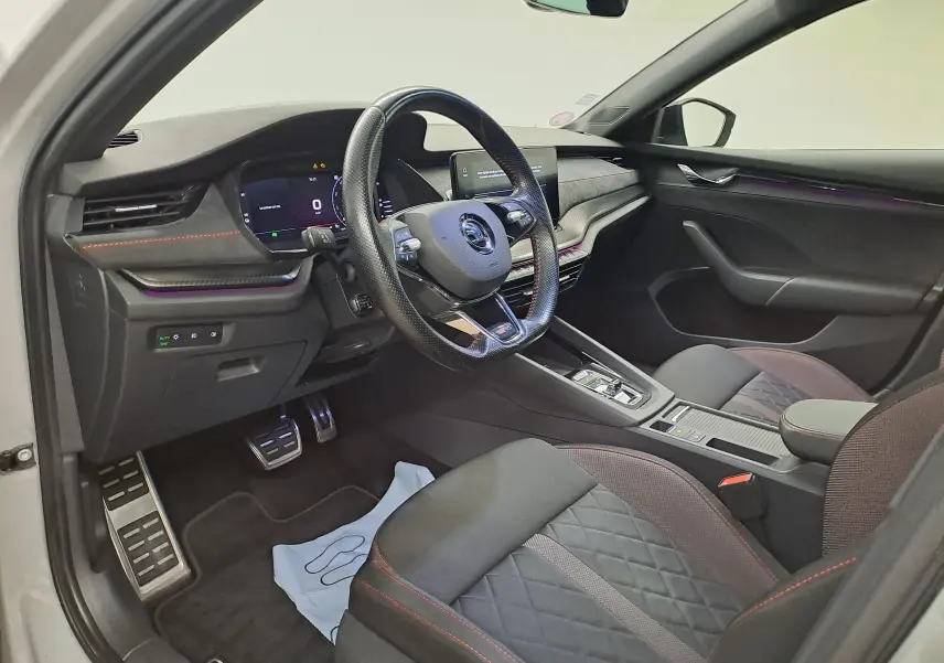 Vue intérieure côté conducteur de la Skoda Octavia Combi 1.4 TSI PHEV 2021 avec sièges noirs et surpiqûres rouges.