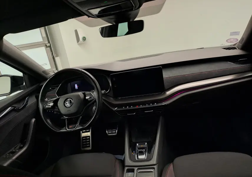 Vue intérieure avant de la Skoda Octavia Combi 1.4 TSI PHEV 245ch DSG6 RS, tableau de bord noir avec éclairage d’ambiance violet.