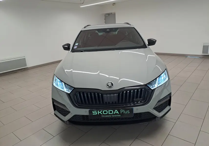 Vue avant d'une Skoda Octavia Combi 1.4 TSI PHEV 245ch gris perle avec phares allumés en intérieur showroom.