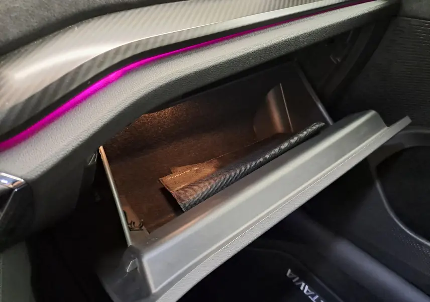 Gros plan sur la boîte à gants ouverte de la Skoda Octavia Combi 1.4 TSI PHEV 245ch RS, avec éclairage intérieur violet.