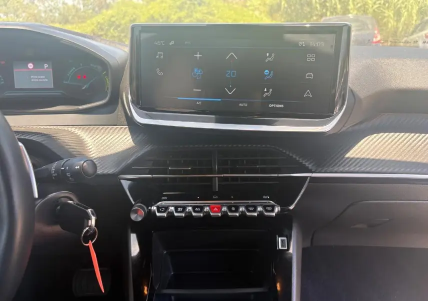 Vue intérieure du tableau de bord du Peugeot 2008 gris 2025, avec écran tactile central et commandes piano noires.