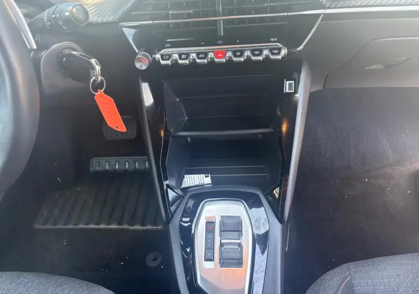 Vue intérieure centrée sur la console centrale et levier de vitesse automatique du Peugeot 2008 gris, avec tableau de bord noir brillant.
