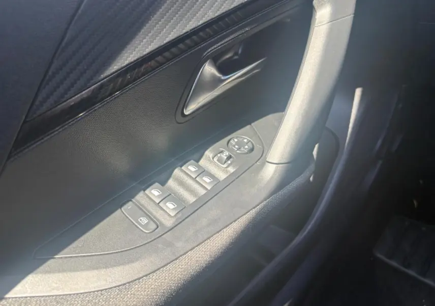 Détail de la porte côté conducteur du Peugeot 2008 gris, montrant les commandes des vitres et rétroviseurs.