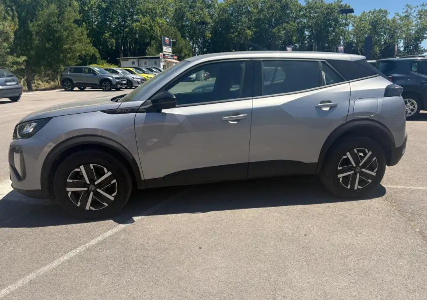 Peugeot 2008 Hybrid 145 gris en profil côté gauche, avec jantes 16 pouces et badge Style près du rétroviseur.