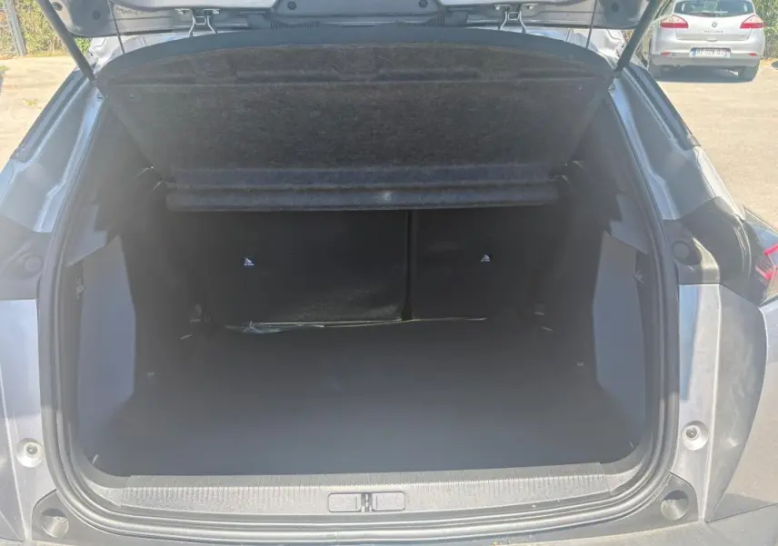 Coffre ouvert en vue arrière du Peugeot 2008 Hybrid 145 gris, mettant en valeur l’espace de chargement.