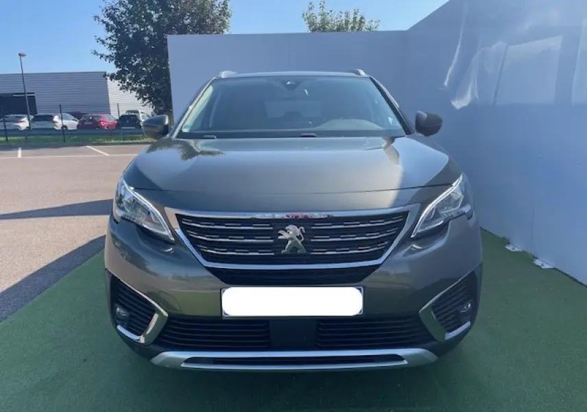 Vue frontale d'un Peugeot 5008 gris amazonite avec calandre chromée et feux LED diurnes intégrés.