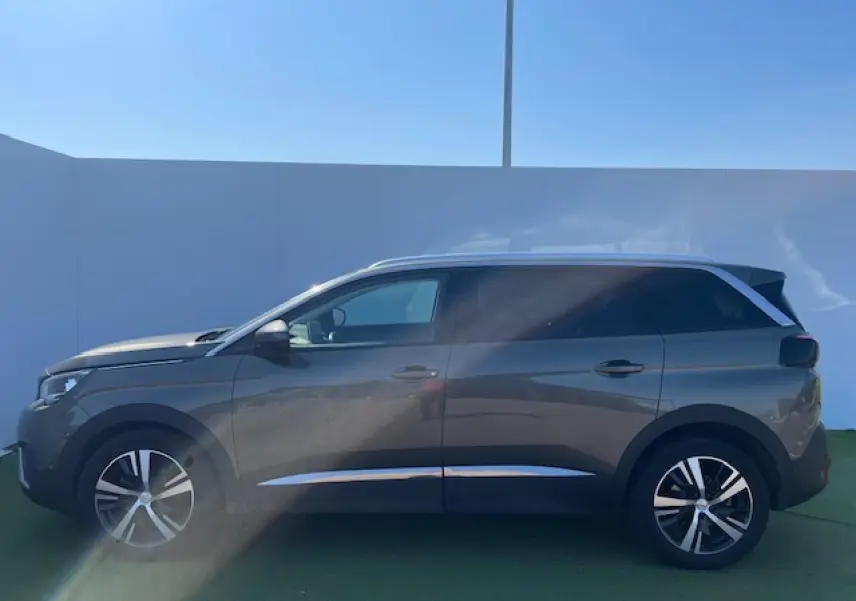 Profil côté gauche d'un Peugeot 5008 gris amazonite avec jantes alliage et vitres surteintées.