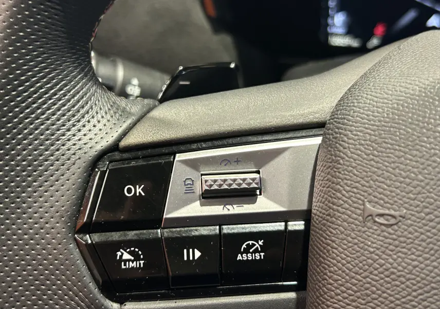 Gros plan sur les commandes au volant en cuir noir du DS4 2024, mettant en valeur les boutons d'assistance et de limitation de vitesse.