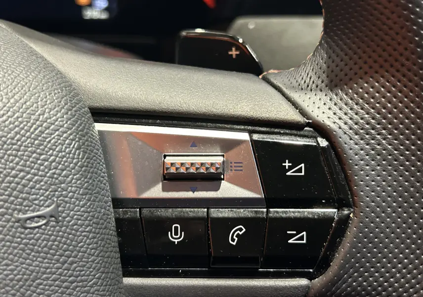 Gros plan sur les commandes vocales et volume au volant en cuir perforé du DS4 noir Perla Nera 2024.