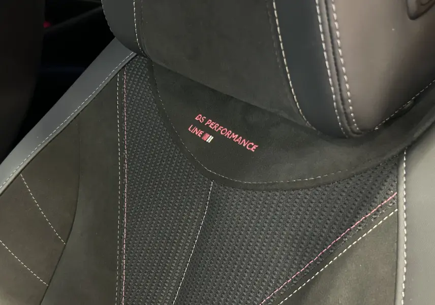 Gros plan sur le siège avant en cuir noir avec surpiqûres rouges et logo DS Performance Line brodé.