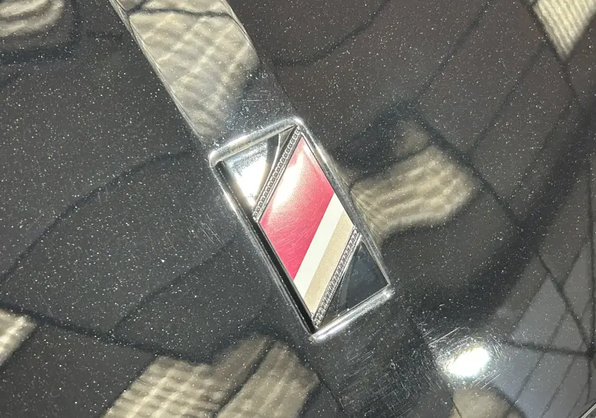 Gros plan sur l'emblème tricolore sur la carrosserie noire Perla Nera du DS4 2024.