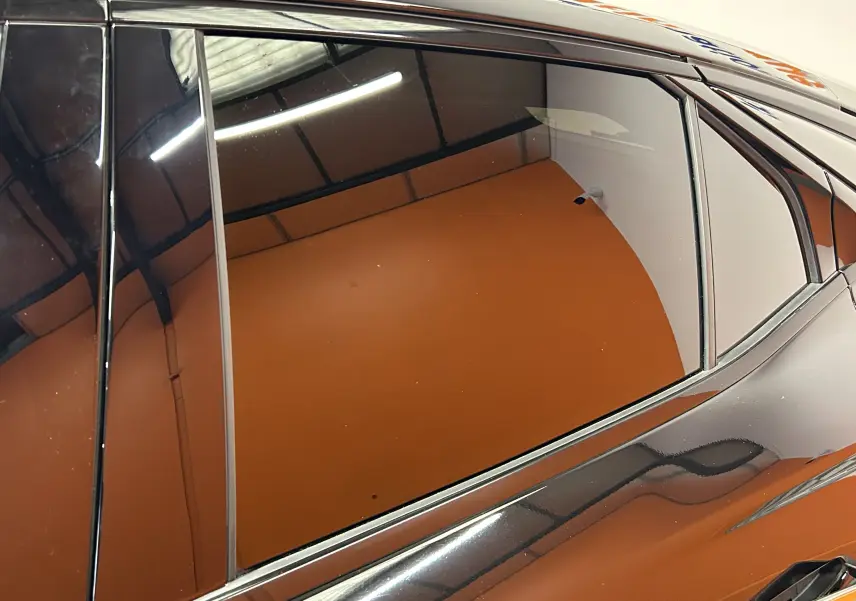 Gros plan sur la porte arrière côté gauche d'une DS4 2024 noire Perla Nera avec vitrage teinté et lignes de carrosserie élégantes.