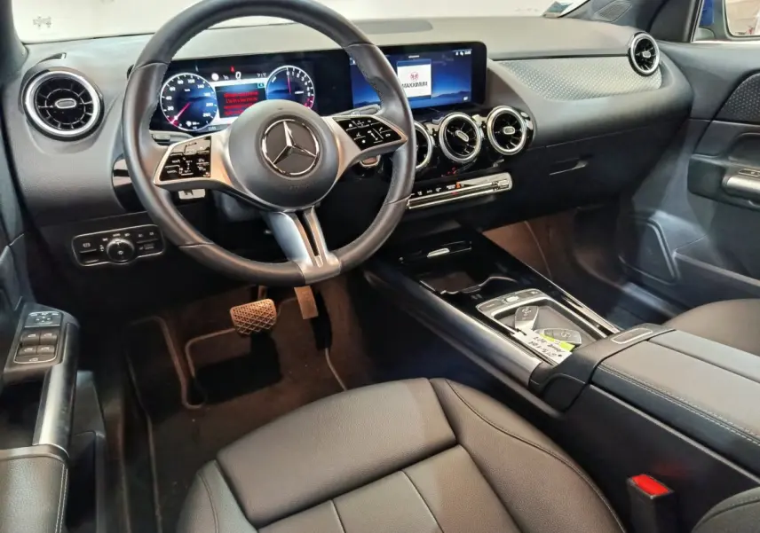 Intérieur avant droit du Mercedes GLA 250 e Business Line 2024, tableau de bord noir avec écran tactile et volant cuir multifonctions.