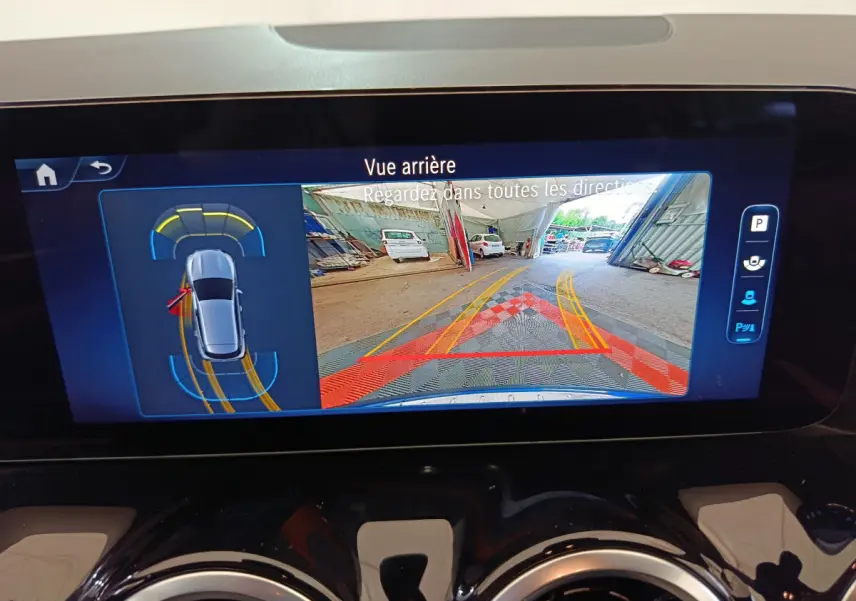 Écran tactile intérieur montrant la caméra de recul et l'aide au stationnement du Mercedes GLA 250 e bleu 2024.