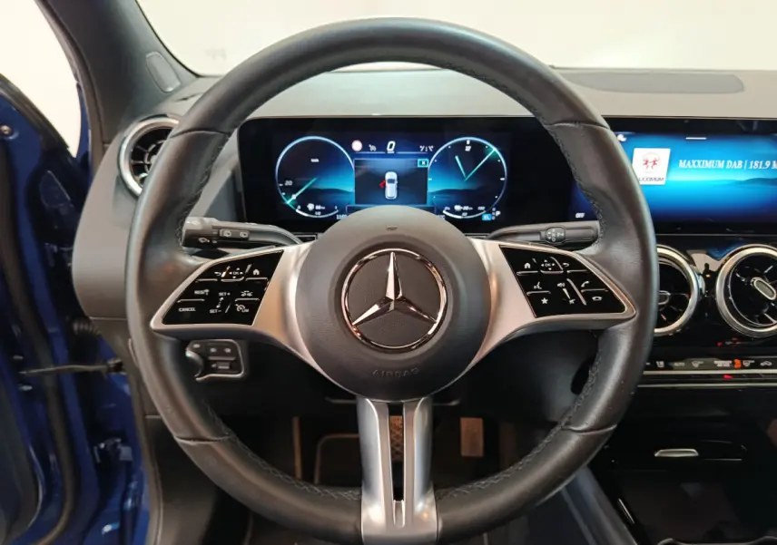 Vue frontale du volant cuir noir de la Mercedes GLA 250 e Business Line 2024 avec tableau de bord numérique et écran tactile.