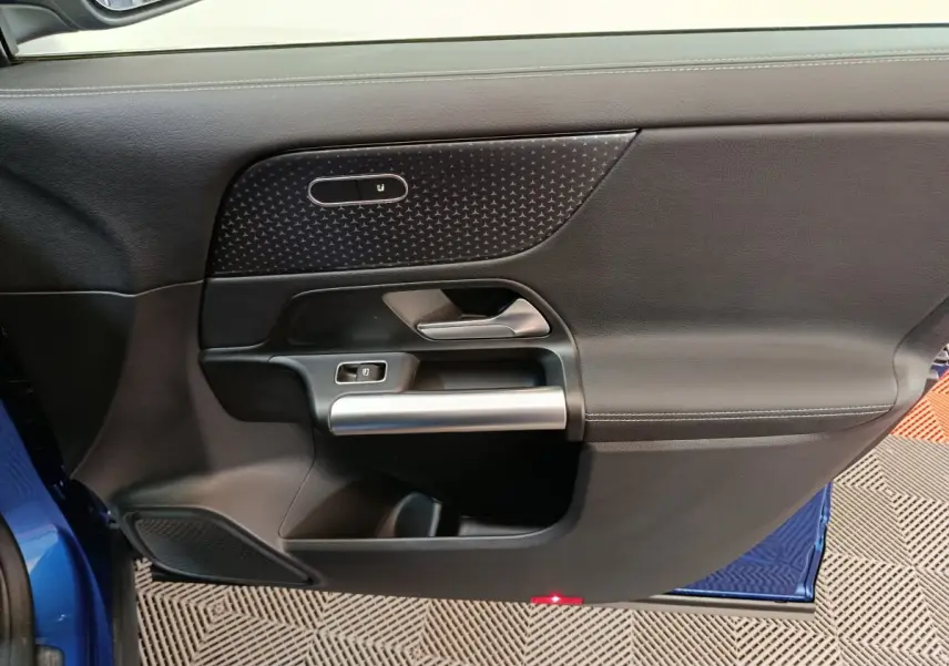 Gros plan sur la porte côté gauche du Mercedes GLA bleu 2024, avec garniture noire et poignée argentée.