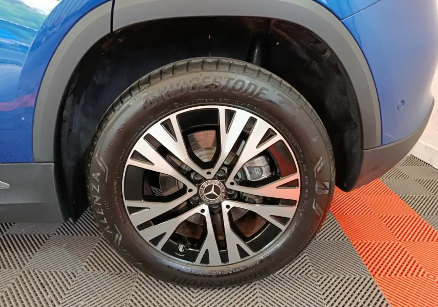 Gros plan sur la roue avant droite d’un Mercedes GLA 250 e bleu, mettant en valeur la jante alliage et le pneu Bridgestone.