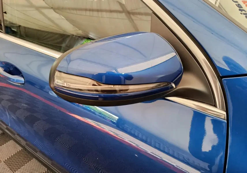 Gros plan sur le rétroviseur côté gauche bleu métallisé d'une Mercedes GLA 250 e Business Line 2024.