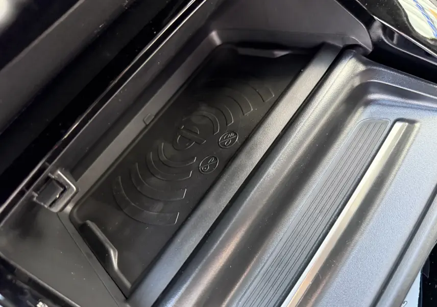 Gros plan sur la zone de recharge sans fil noire dans l'habitacle du Peugeot 2008 Hybrid 145ch GT 2025.