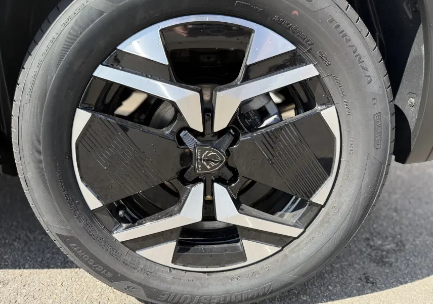 Gros plan sur la jante avant droite noire et argentée du Peugeot 2008 Hybrid 145ch gris Artense toit noir 2025.