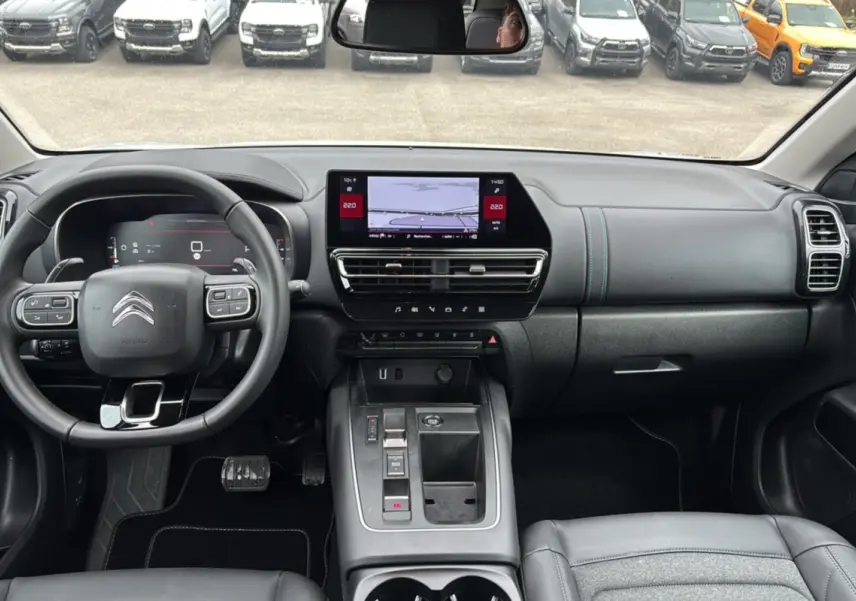 Vue intérieure du poste de conduite du Citroën C5 Aircross Hybrid blanc, avec tableau de bord numérique et écran central tactile.