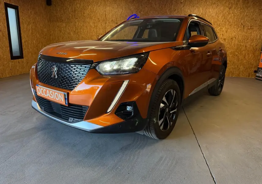 Peugeot 2008 orange vue 3/4 avant droit avec calandre noire et feux LED allumés en intérieur.