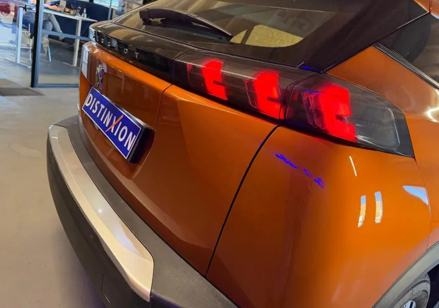 Vue 3/4 arrière droite du Peugeot 2008 orange avec feux arrière LED en forme de griffes et becquet noir brillant.