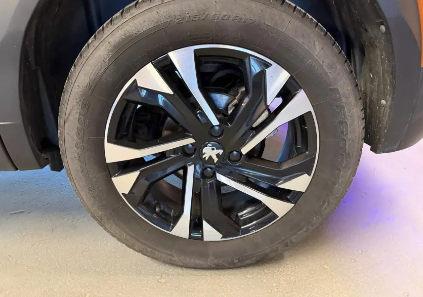 Gros plan sur la jante alliage 17'' bi-ton noir et argent avec logo Peugeot au centre du Peugeot 2008 orange.