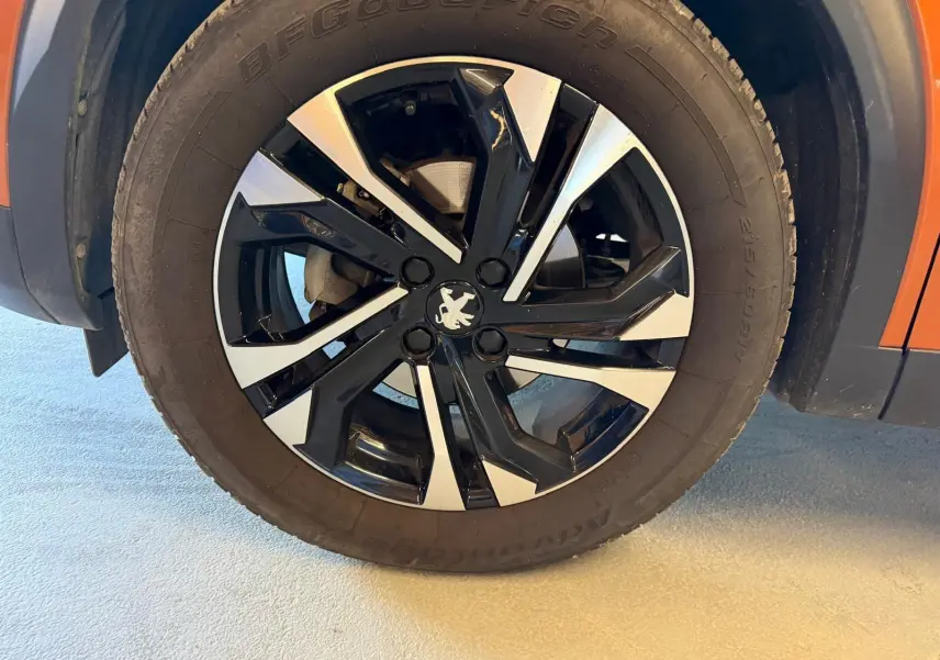 Gros plan sur la jante alliage 17'' bi-ton noir et argent du côté gauche d’un Peugeot 2008 orange.