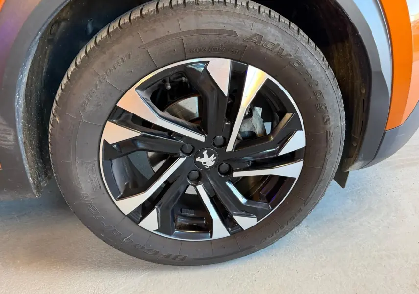 Gros plan sur la jante alliage 17'' bi-ton noir et argent du côté avant gauche d’un Peugeot 2008 orange.