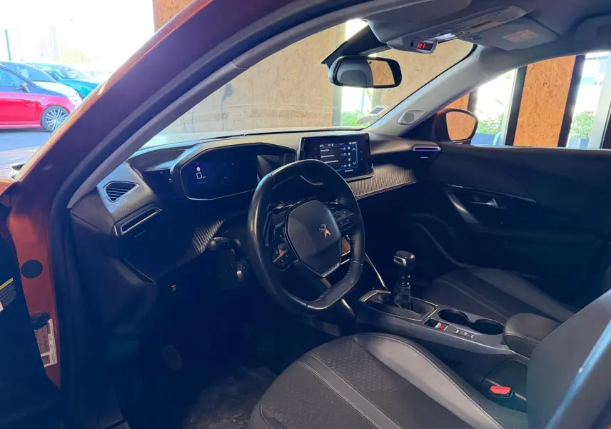 Intérieur de la Peugeot 2008 orange vue côté conducteur, volant compact, tableau de bord numérique et boîte manuelle.