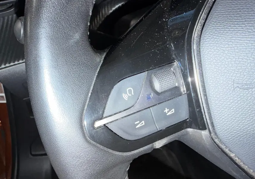 Gros plan sur les commandes multimédia noires du volant cuir du Peugeot 2008 Orange Fusion 2020.