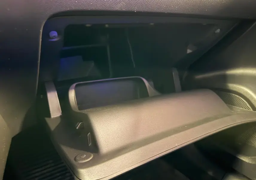 Gros plan sur la boîte à gants ouverte de la Peugeot 2008 1.5 BlueHDi 100 Allure, intérieur noir.